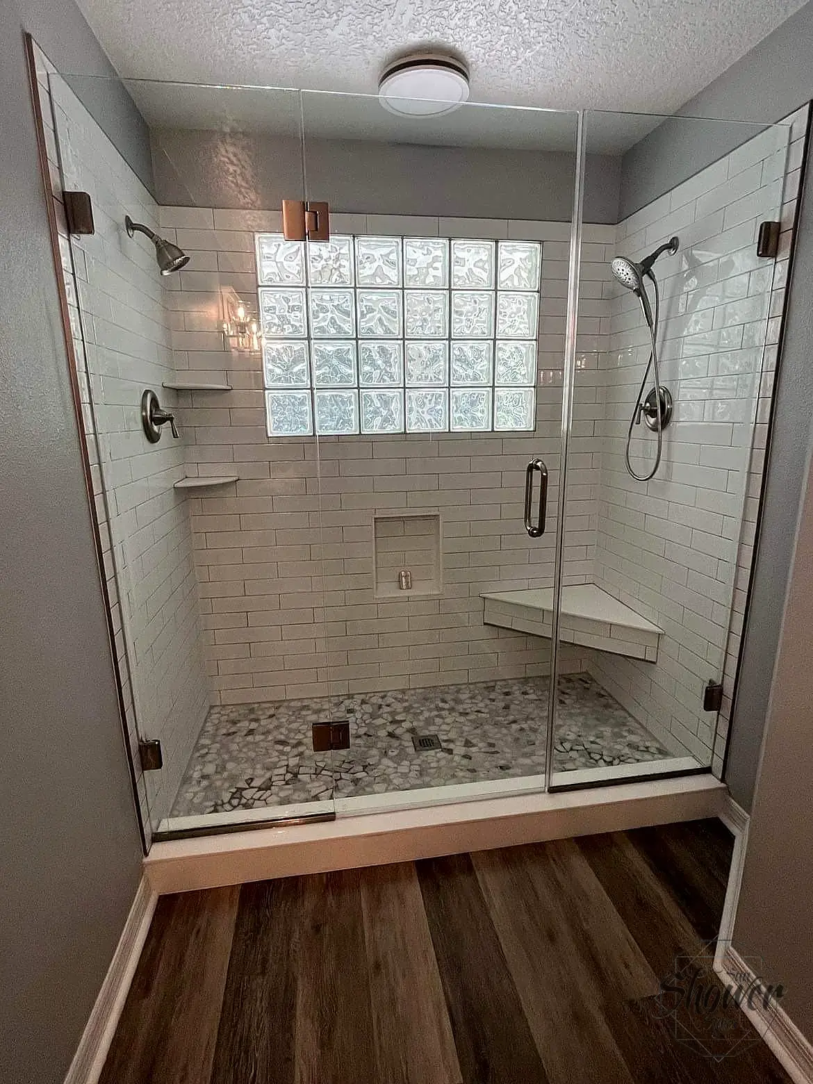 Glass shower enclosure with white tile and natural light